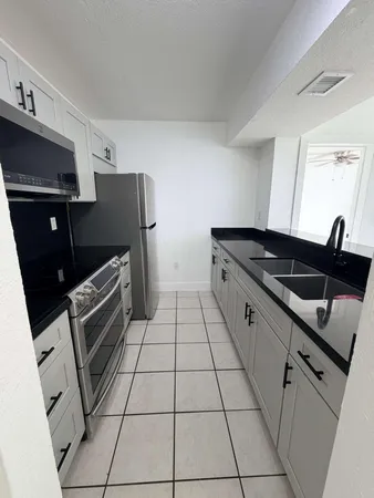 a kitchen with granite countertop a refrigerator and a sink