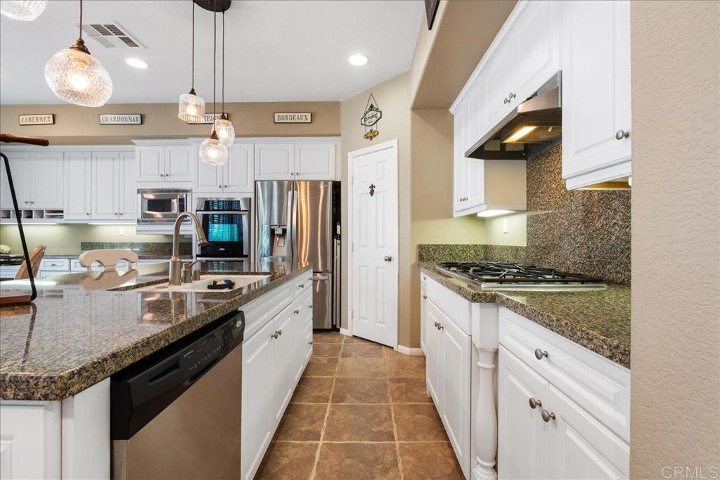 2667 Fallsview Road San Marcos, CA 92078 - Photo 23 of 54 a large kitchen with stainless steel appliances granite countertop a stove a refrigerator and a granite counter tops