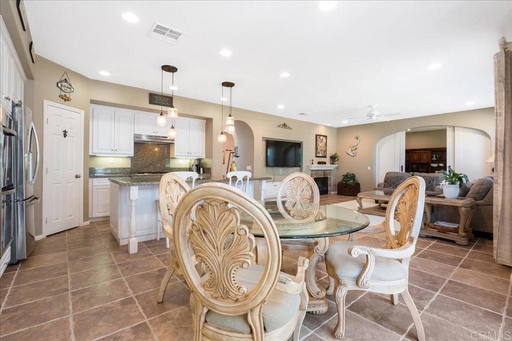 2667 Fallsview Road San Marcos, CA 92078 - Photo 26 of 54 a kitchen with stainless steel appliances kitchen island granite countertop a table chairs and a refrigerator