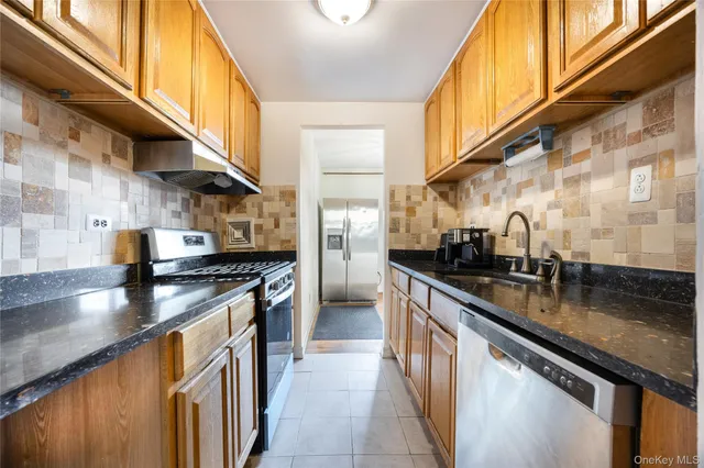 a kitchen with stainless steel appliances granite countertop a stove a sink and a refrigerator