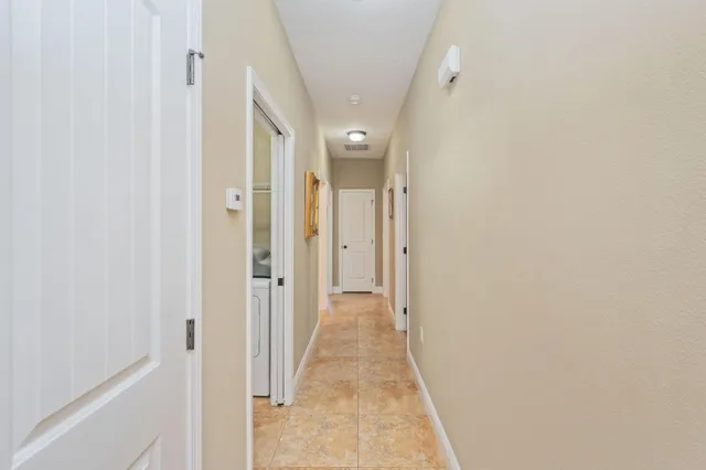 a view of a hallway with wooden floor and a bathroom