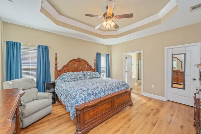 a bedroom with a large bed a chandelier and dresser