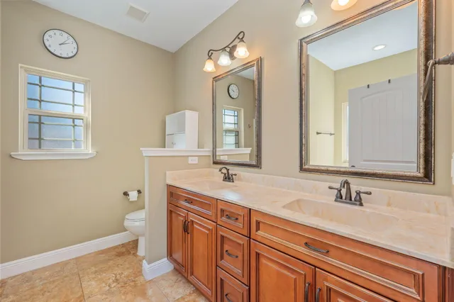 a bathroom with double vanity sink a mirror and a toilet