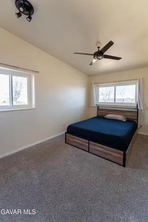 an empty room with windows and ceiling fan