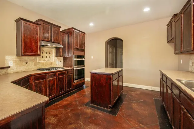 a kitchen with stainless steel appliances granite countertop a stove a sink and a refrigerator