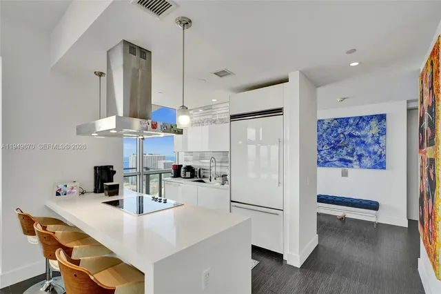 a kitchen with stainless steel appliances a refrigerator a sink a stove a dining table and chairs