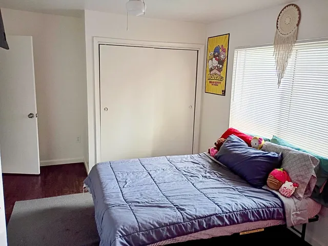 a bedroom with a bed and a dresser next to a window
