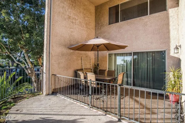 a view of a balcony with chairs and umbrella