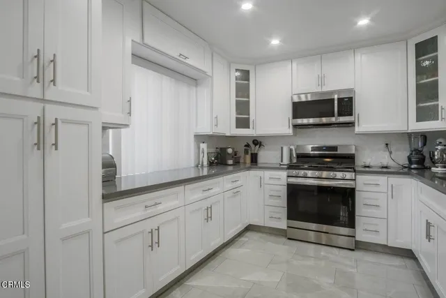 a kitchen with white cabinets stainless steel appliances and a window