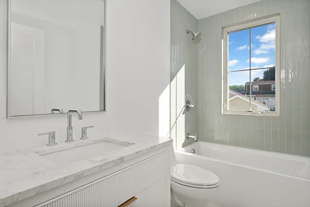 a bathroom with a granite countertop sink a toilet and shower