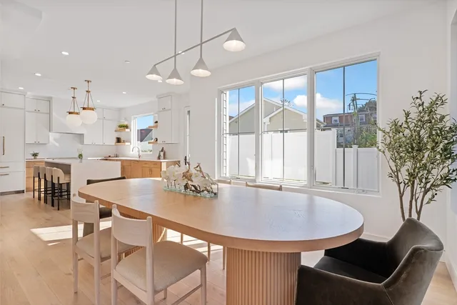 a dining room with stainless steel appliances furniture a large window and kitchen view