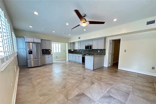 a large kitchen with stainless steel appliances granite countertop a refrigerator and a stove top oven