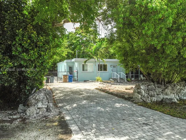 a front view of a house with a garden and tree