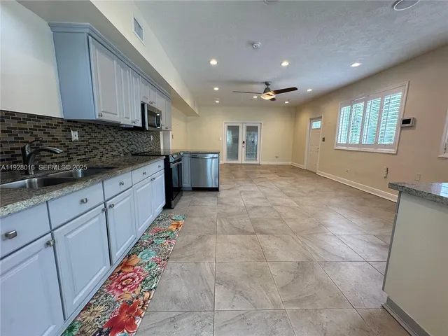 a large kitchen with stainless steel appliances granite countertop a sink and cabinets
