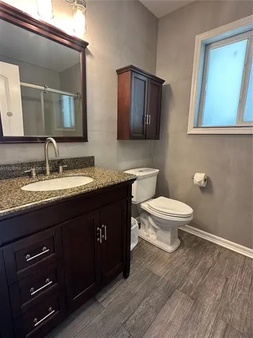 a bathroom with a granite countertop toilet sink and mirror