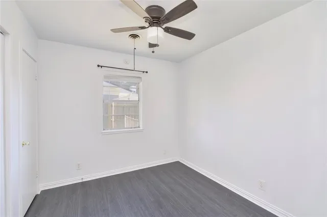 an empty room with a window and a fan