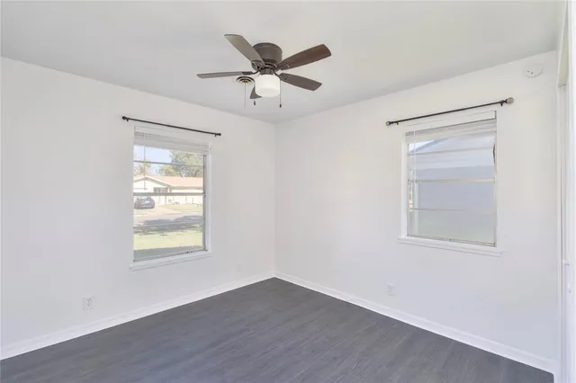 an empty room with wooden floor closet and windows