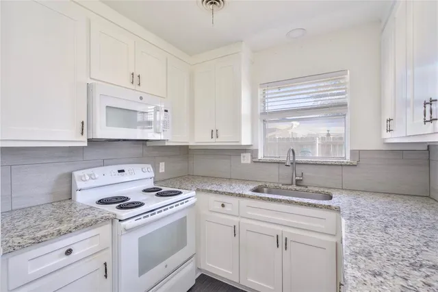 a kitchen with kitchen island white cabinets white stainless steel appliances a sink and a window