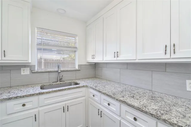 a kitchen with granite countertop white cabinets and a sink