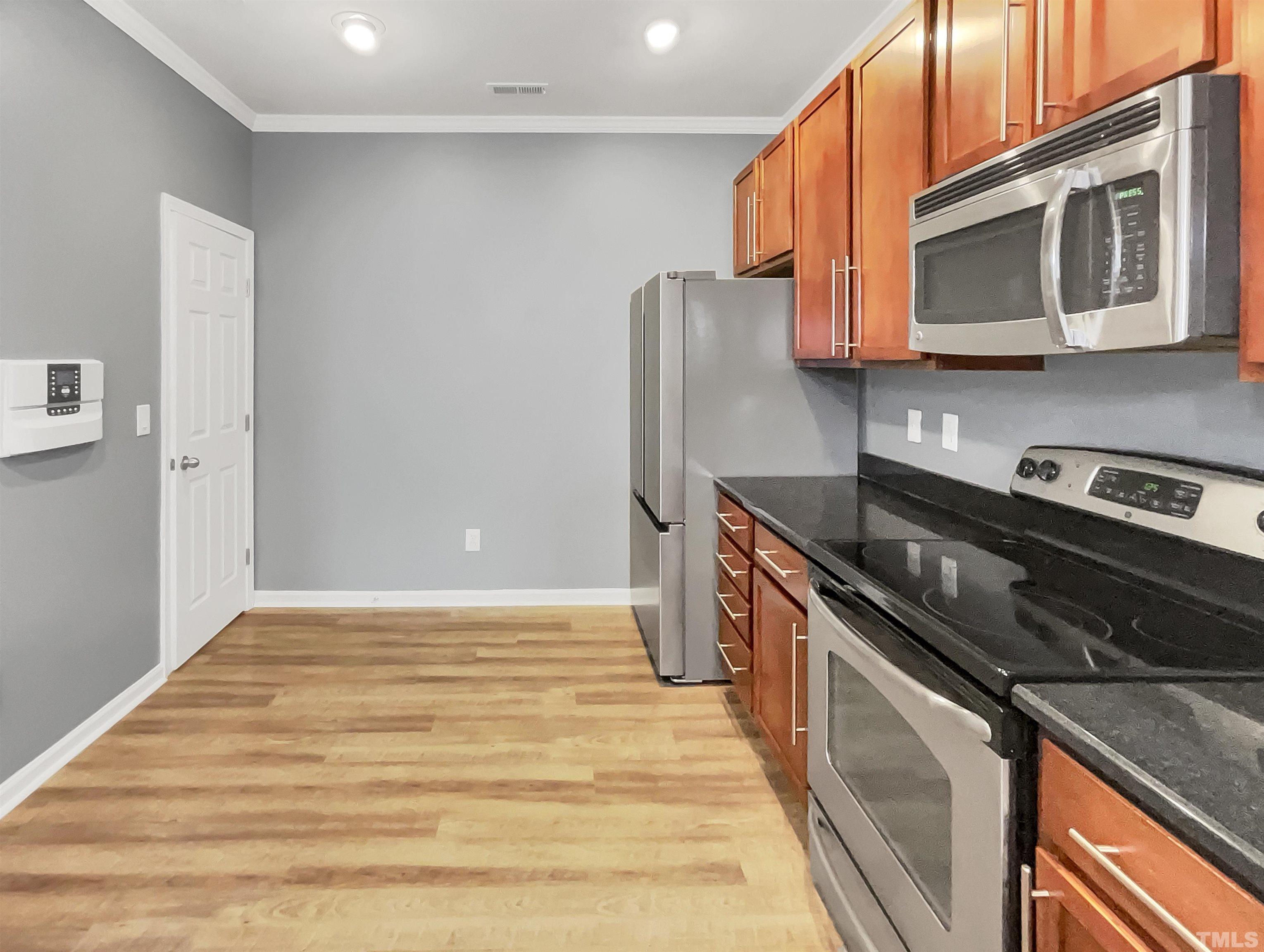 1111 Consortium Drive, Unit 101 Raleigh, NC 27603 - Photo 6 of 17 a kitchen with stainless steel appliances granite countertop a refrigerator and a stove top oven