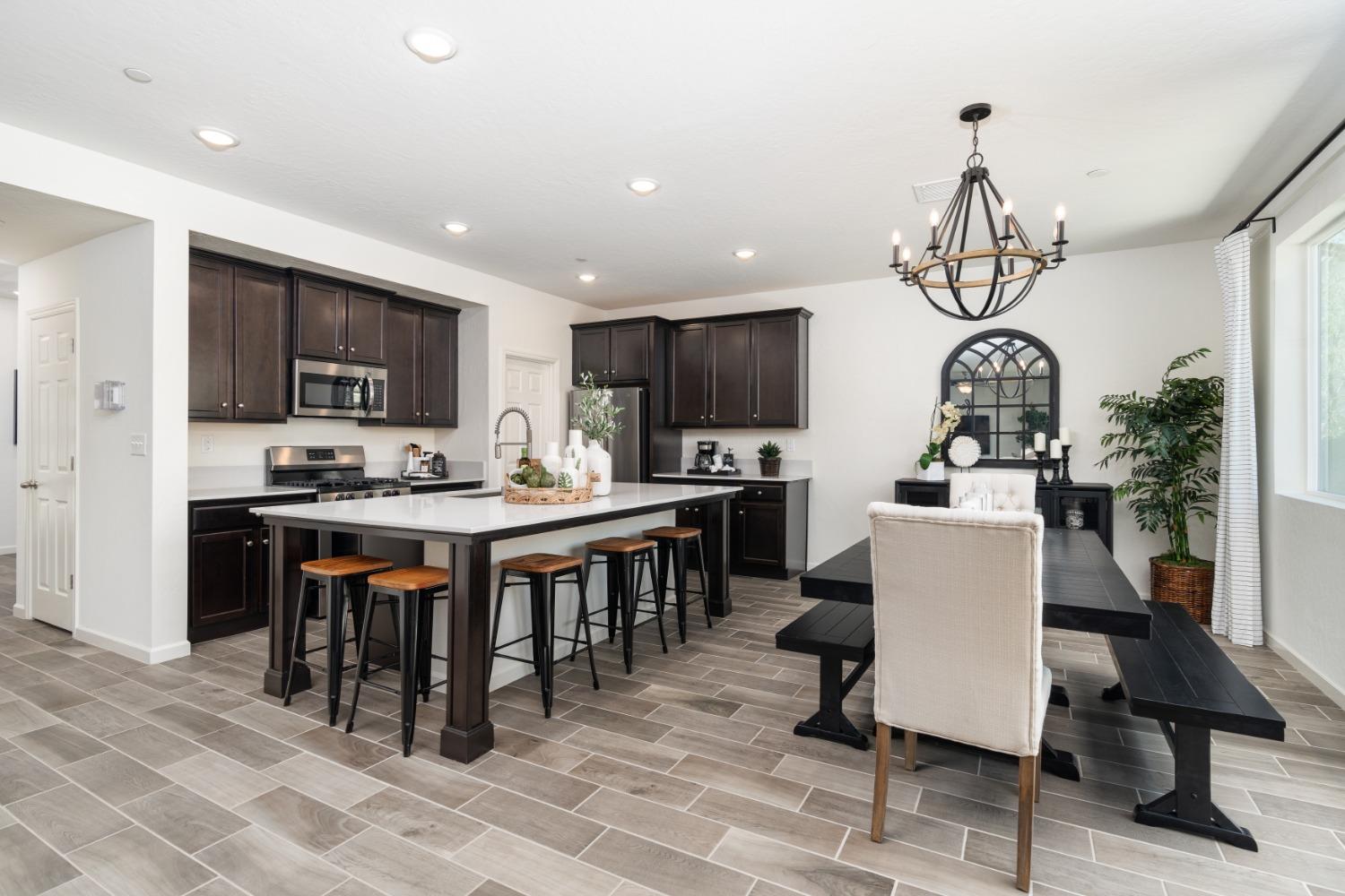 1198 Significant Way West Madera, CA 93636 - Photo 13 of 29 a kitchen with stainless steel appliances granite countertop a stove top oven a sink dishwasher a dining table and chairs with wooden floor