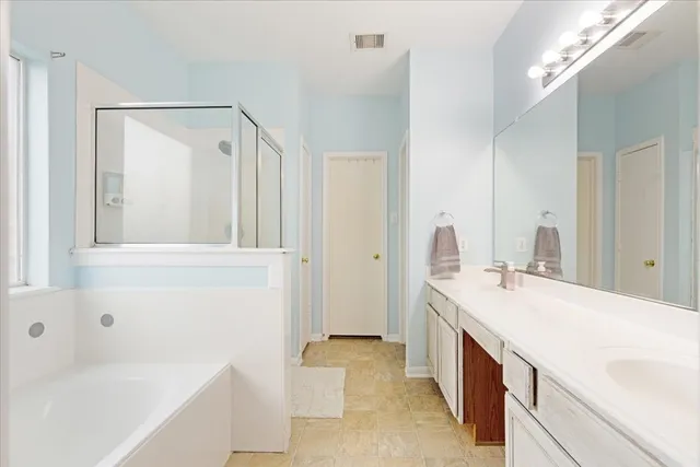 a spacious bathroom with a tub sink and mirror