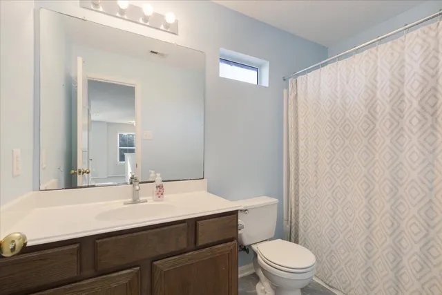 a bathroom with a sink a toilet a mirror and shower curtain