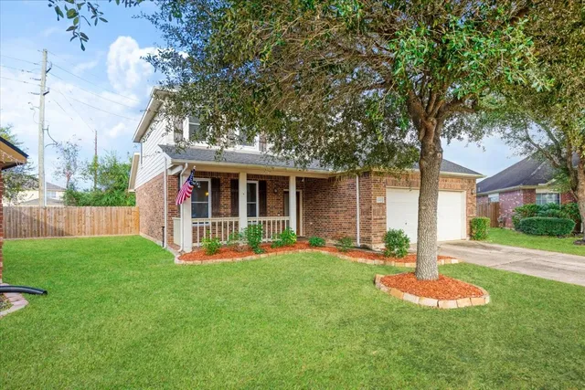 front view of a house with a yard and a large tree