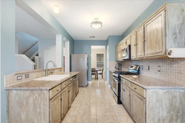 a kitchen with stainless steel appliances granite countertop a sink stove and cabinets