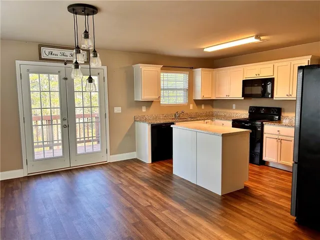 a kitchen with stainless steel appliances granite countertop a stove top oven a sink with wooden floors and cabinets