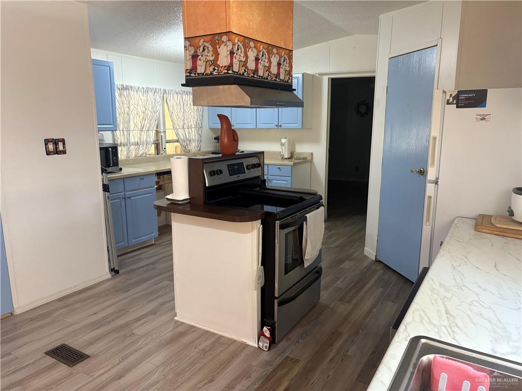 2515 Meadowlark Street Palmview, TX 78572 - Photo 13 of 26 Kitchen featuring stainless steel electric stove, blue cabinets, wood finished floors, freestanding refrigerator, and a textured ceiling