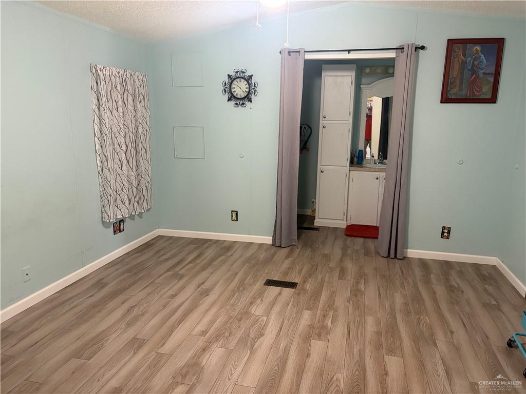 2515 Meadowlark Street Palmview, TX 78572 - Photo 14 of 26 Unfurnished bedroom featuring light wood-style floors and a textured ceiling