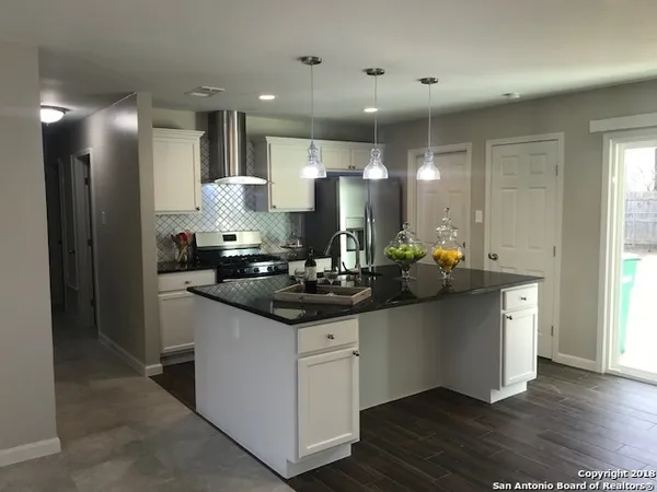 a kitchen with stainless steel appliances kitchen island a sink and a large window