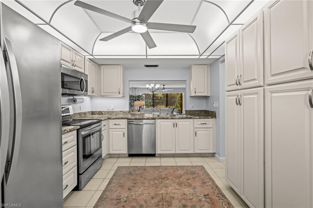 500 Misty Pines Circle, Unit 2103 Naples, FL 34105 - Photo 5 of 38 a kitchen with stainless steel appliances granite countertop a sink a stove a refrigerator and cabinets