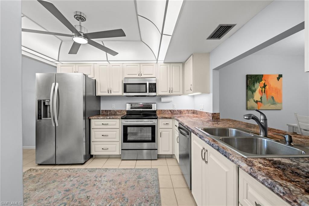 500 Misty Pines Circle, Unit 2103 Naples, FL 34105 - Photo 7 of 38 a kitchen with stainless steel appliances granite countertop a sink a stove a microwave a refrigerator and cabinets