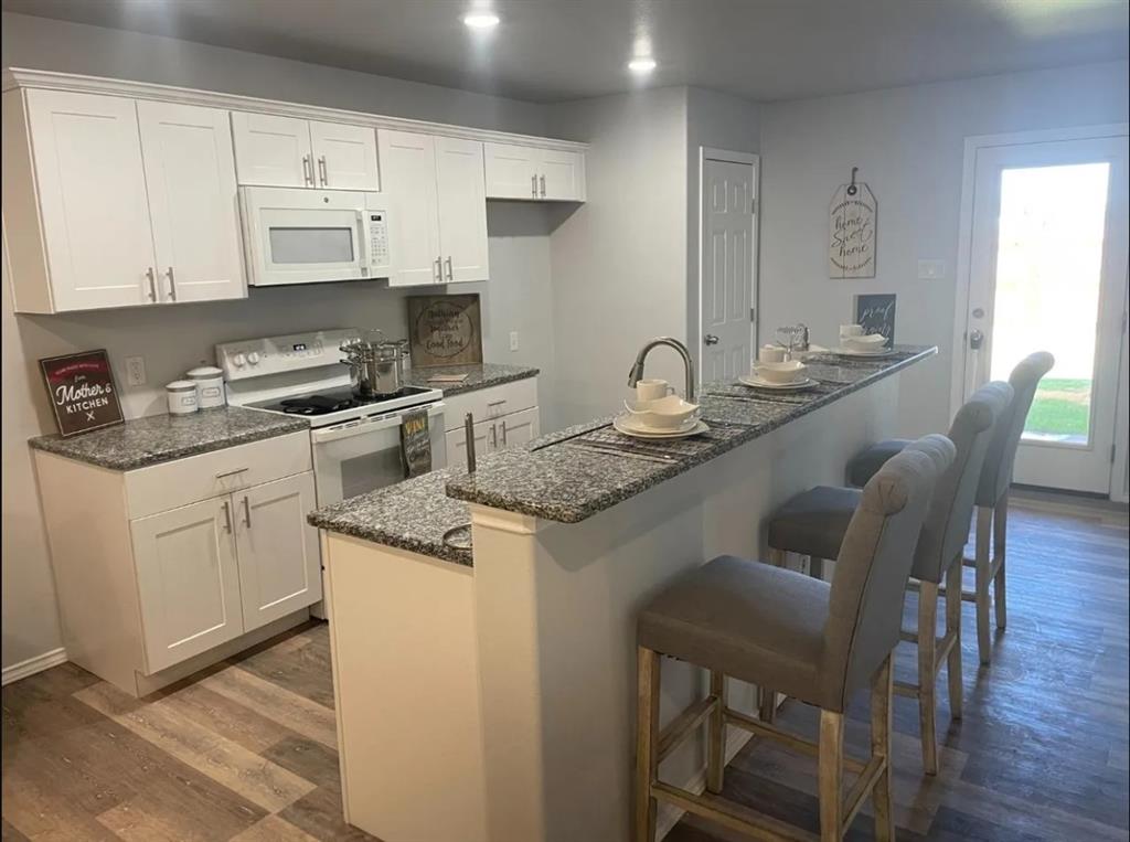 8424 10th Place Lubbock, TX 79416 - Photo 3 of 14 a kitchen with stainless steel appliances granite countertop a white cabinets and a stove top oven