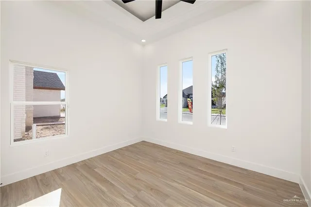 a view of an empty room with a window and wooden floor