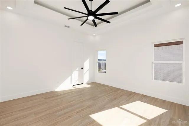 an empty room with wooden floor fan and windows