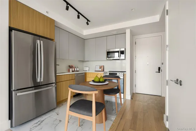 a kitchen with stainless steel appliances granite countertop a refrigerator a sink a stove and white cabinets with wooden floor