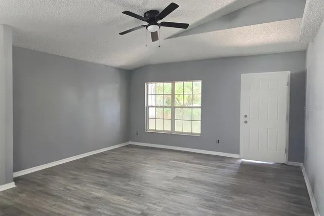 a view of empty room with wooden floor and fan
