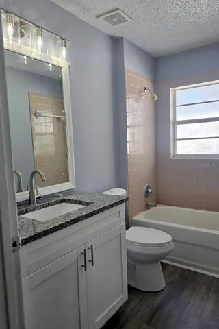 a bathroom with a granite countertop toilet sink and mirror