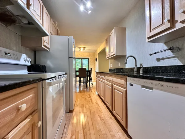 a kitchen with granite countertop a sink a stove top oven and cabinetry