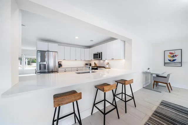 a kitchen with stainless steel appliances a dining table chairs and a refrigerator