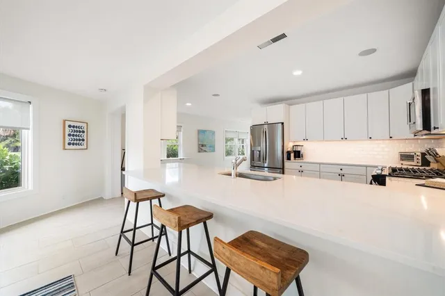 a kitchen with stainless steel appliances kitchen island granite countertop a stove a refrigerator a sink a table and chairs