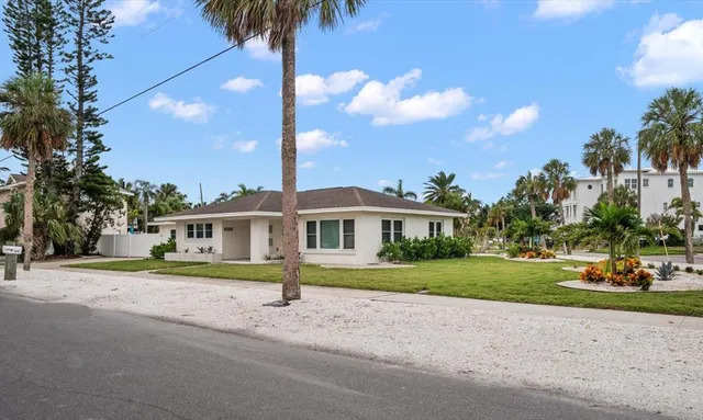 a front view of a house with a garden and trees