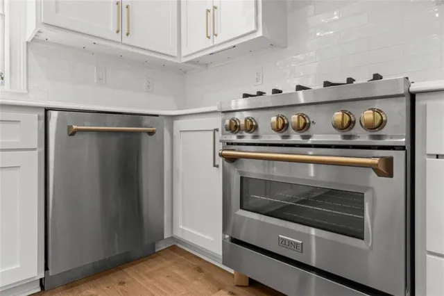 a kitchen with stainless steel appliances granite countertop a stove and a wooden floors