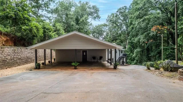 a view of a house with large trees and wooden fence