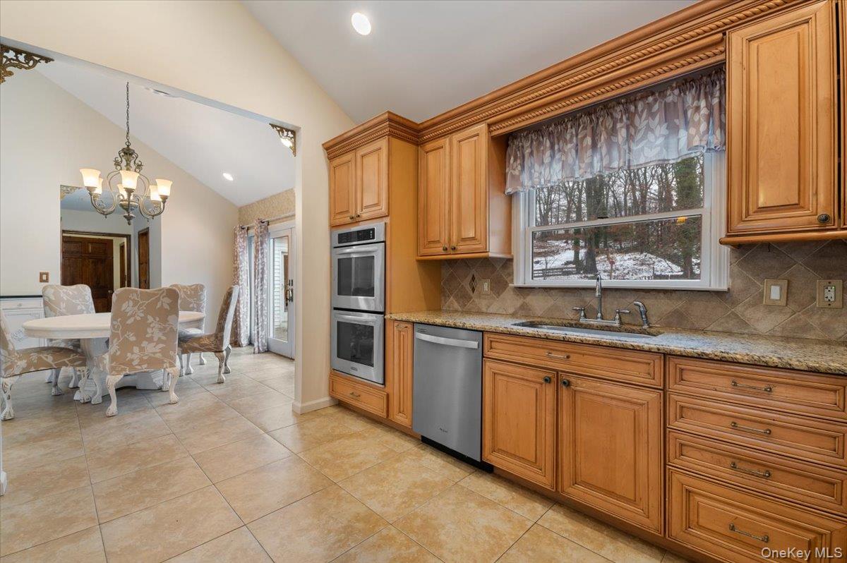 33 Fleets Cove Road Huntington, NY 11743 - Photo 14 of 42 Kitchen featuring light stone countertops, appliances with stainless steel finishes, tasteful backsplash, recessed lighting, and brown cabinetry