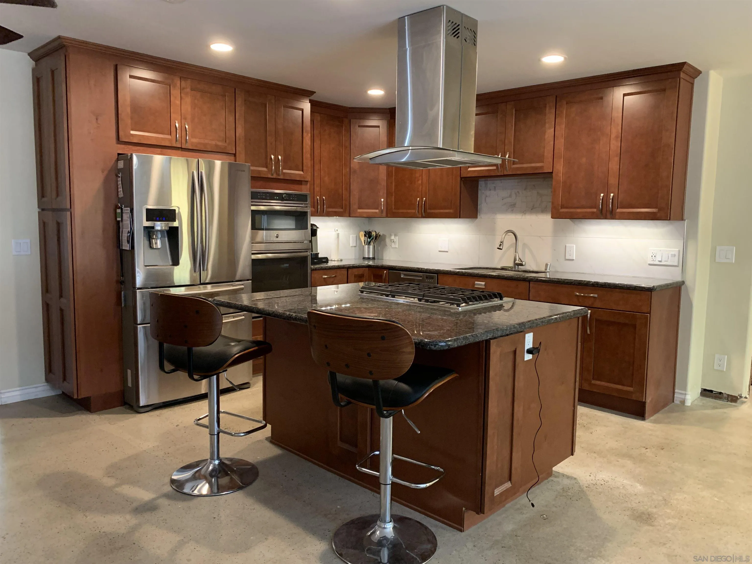 a kitchen with kitchen island granite countertop wooden cabinets and stainless steel appliances