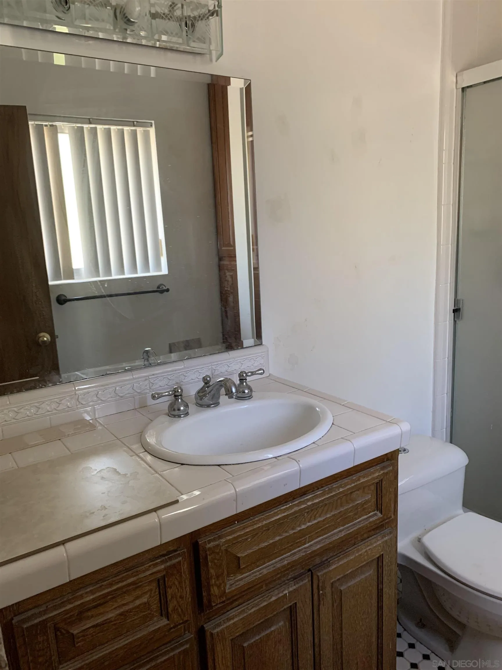 9935 Blossom Valley Road El Cajon, CA 92021 - Photo 15 of 36 a bathroom with a sink a toilet and mirror